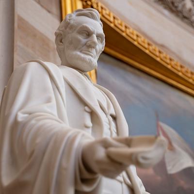 white marble bust of abraham lincoln with a long face and beard staring downwards