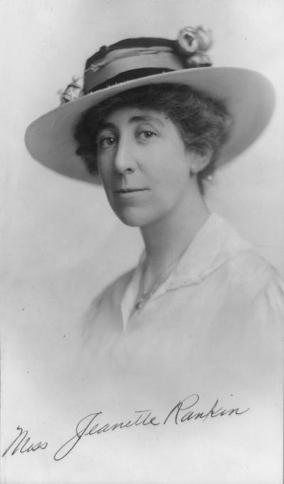 black and white photo of a woman wearing a hat with flowers on it smiling