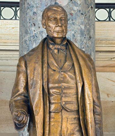 bronze statue of a man with a suit on raising his right arm