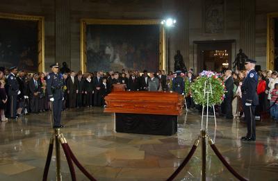 casket in the middle of rotunda with two guards guarding it and a large crowd circled around it