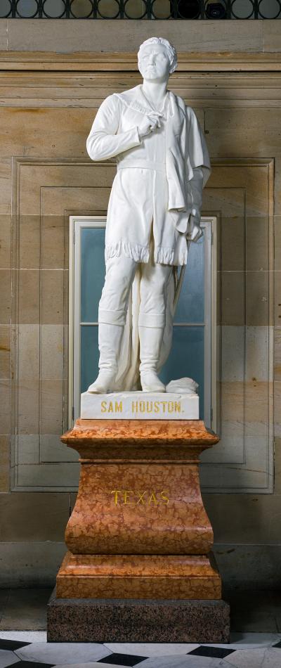 white marble statue of a man with one hand on his collar standing on a red marble stand that says texas
