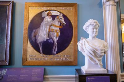 white marble bust of a woman with a draped dress and behind her is a portrait of a woman in a white dress riding a white horse 