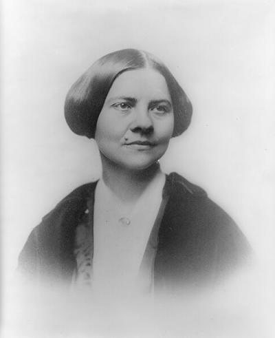 black and white photo of a woman staring to the right with her hair up and a mole on her face