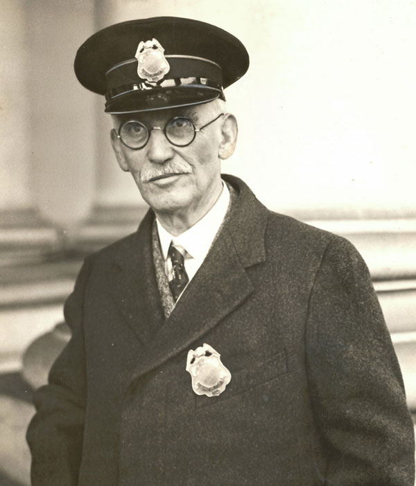 A black and white photo of a man in a jacket and hat.