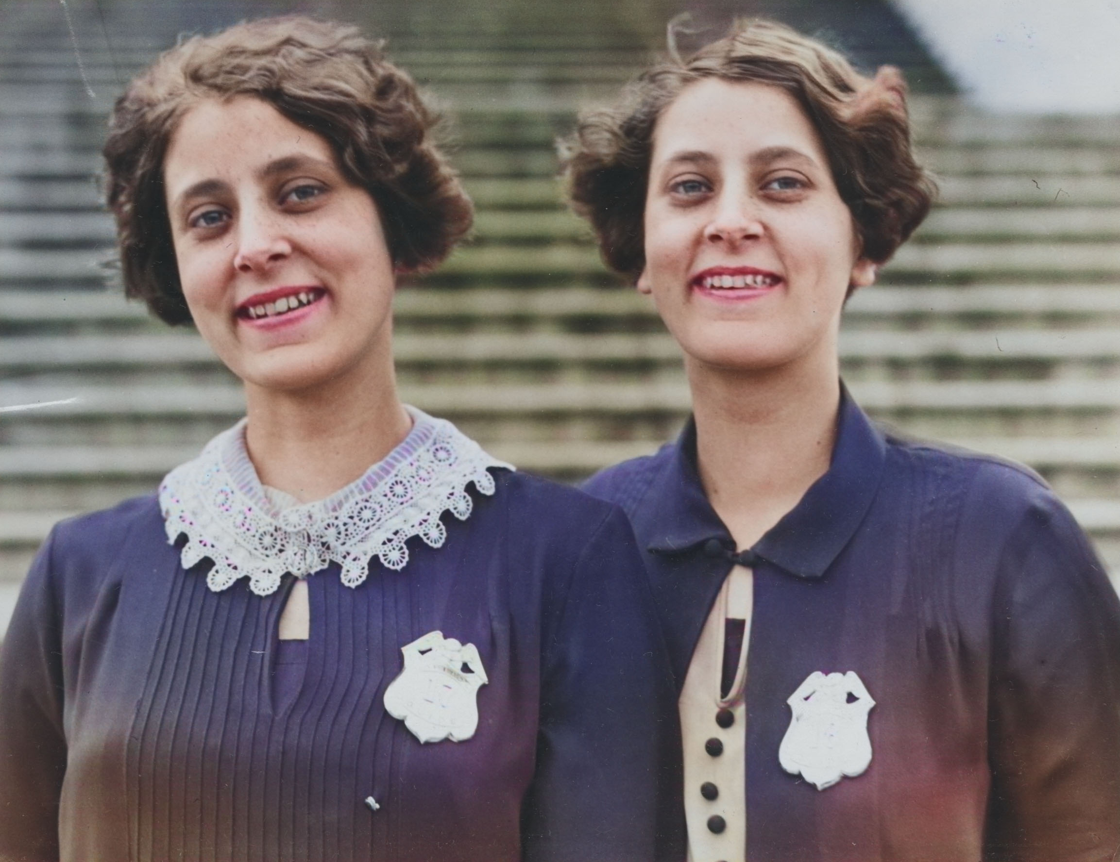 A colorized photo of two identical women smiling.