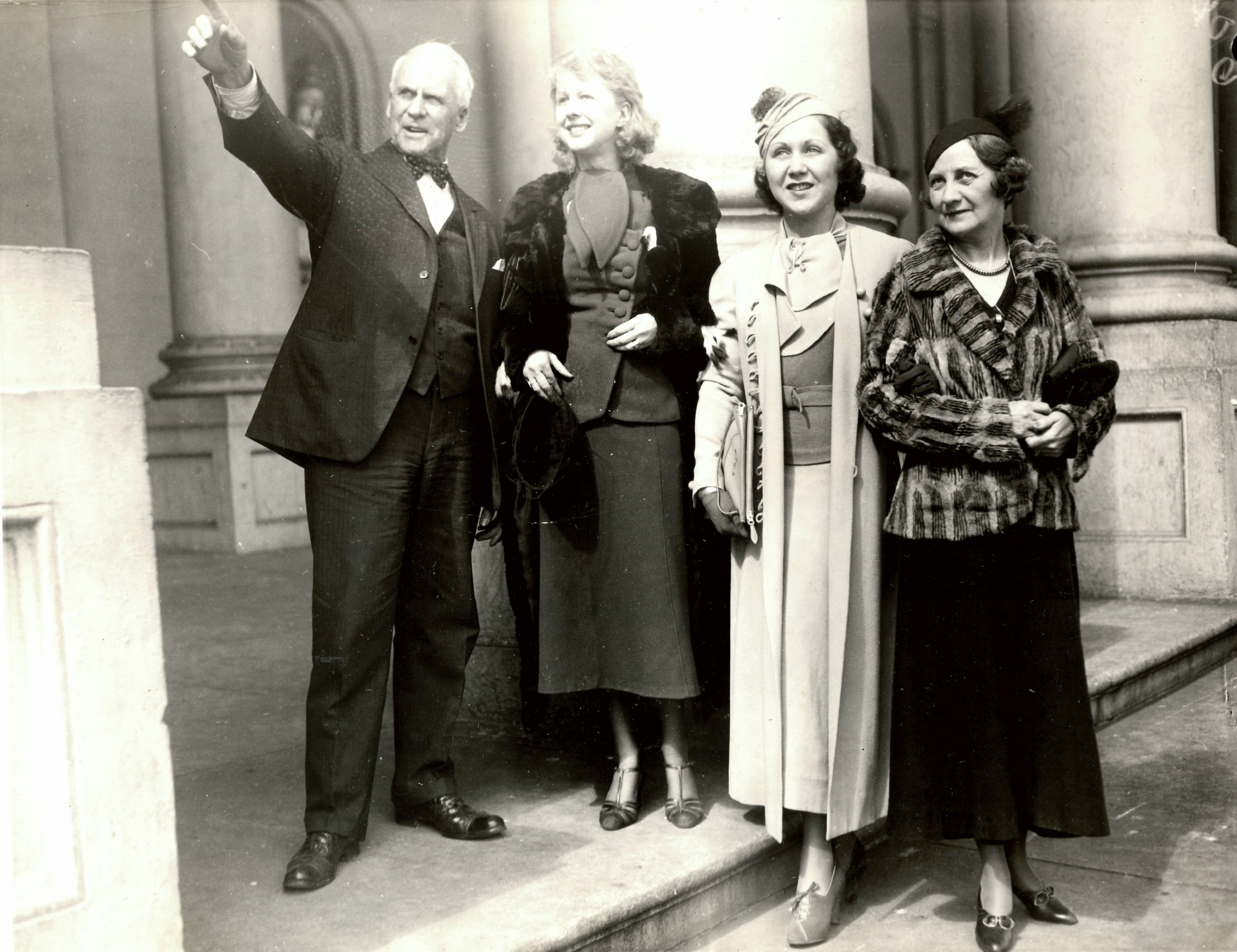 Black and white photo of a man and three women standing on the Capitol steps.