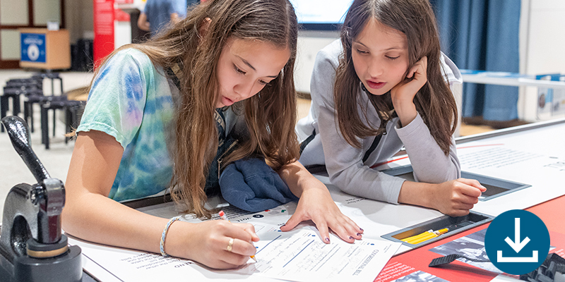Click to view/download this workbook as a pdf. Two girls at a table writing.