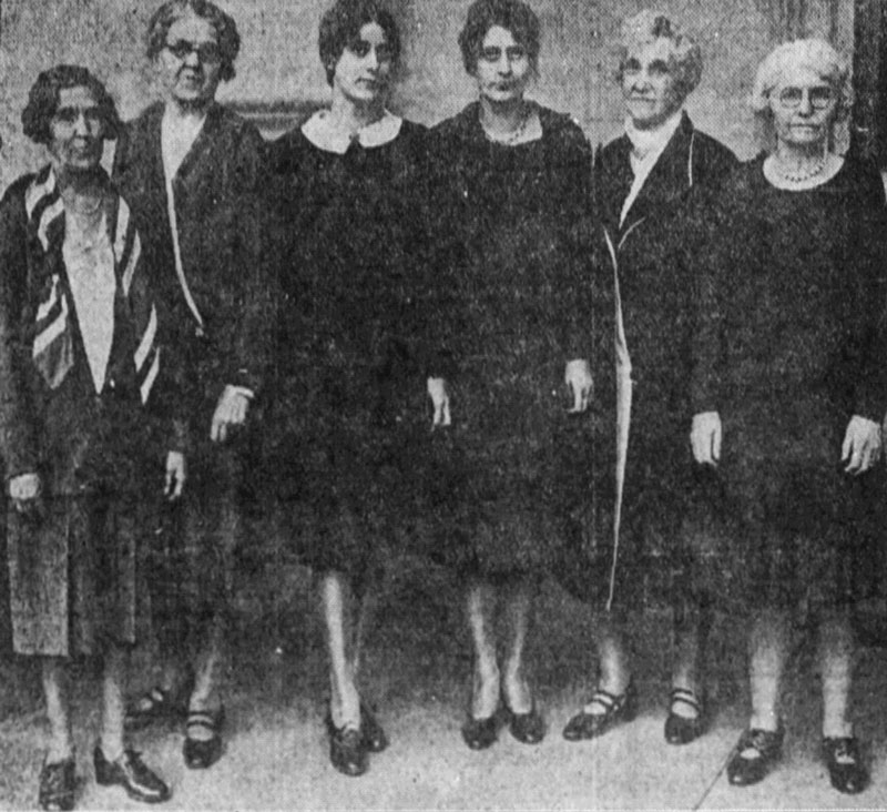A black and white photo of six women wearing dresses