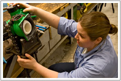 a handywoman works on fixing an item at the edge of a desk 