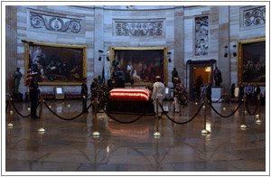 a casket in the capitol rotunda surrounded by barriers and people