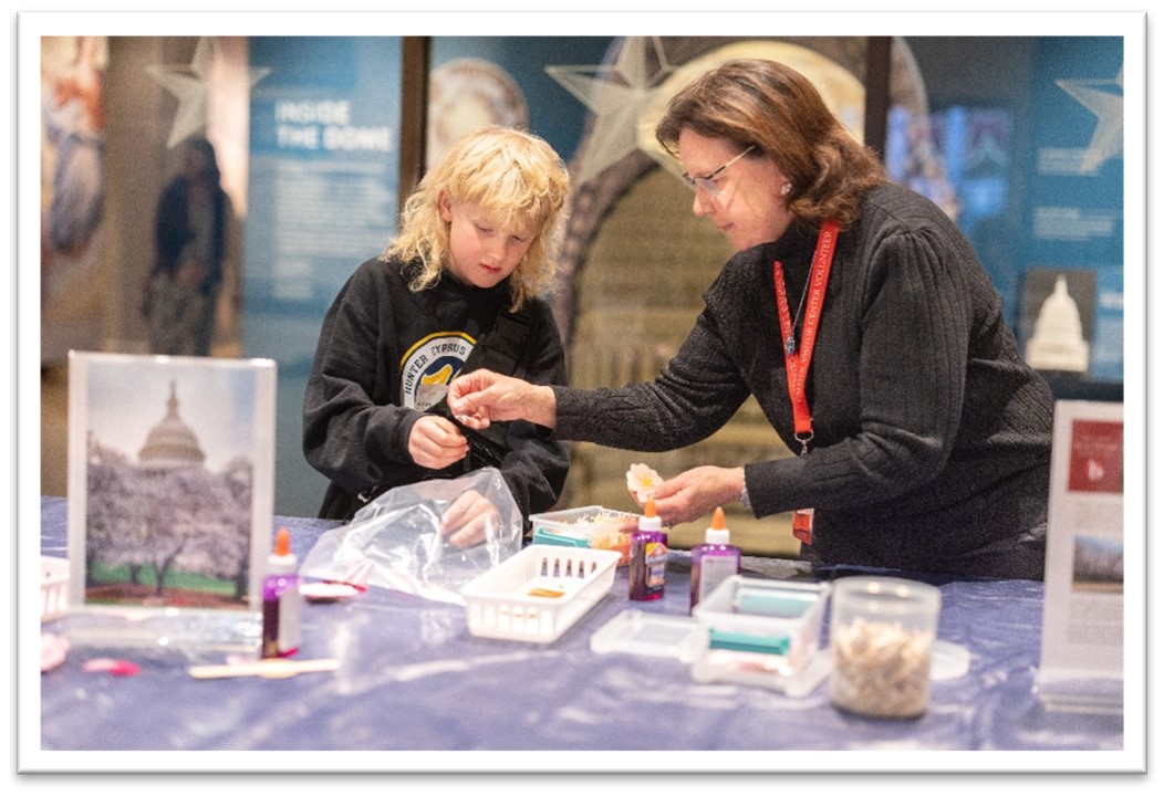 Woman interacting with a child at a craft table.