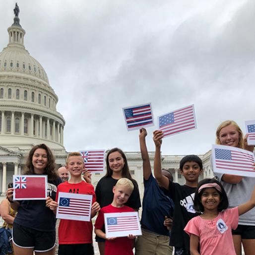 group of middle school students standing in front of the U.S. Capitol Dome holding small paper flags