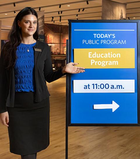Woman standing next to info board. 