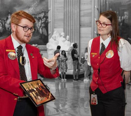 one Visitor Guide wearing a red blazer and one Visitor Guide wearing a red vest