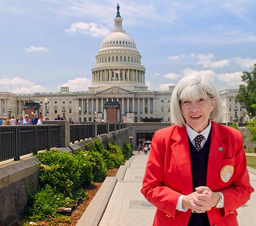 Visitor Guide in a red blazer standing outside in front of the U.S. Capitol