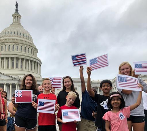 group of middle school students standing in front of the U.S. Capitol Dome holding small paper flags