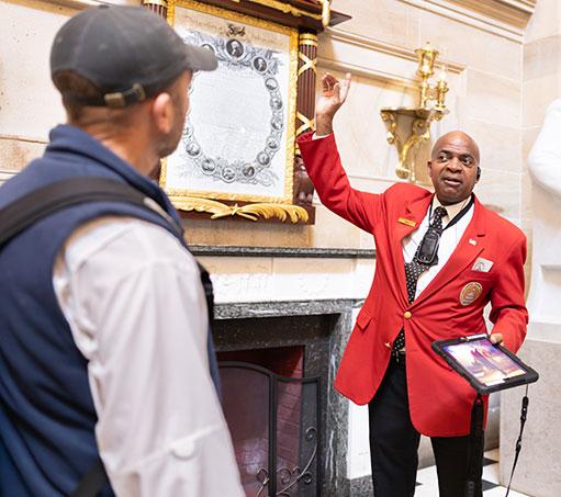 Visitor Guide in a red blazer pointing upwards