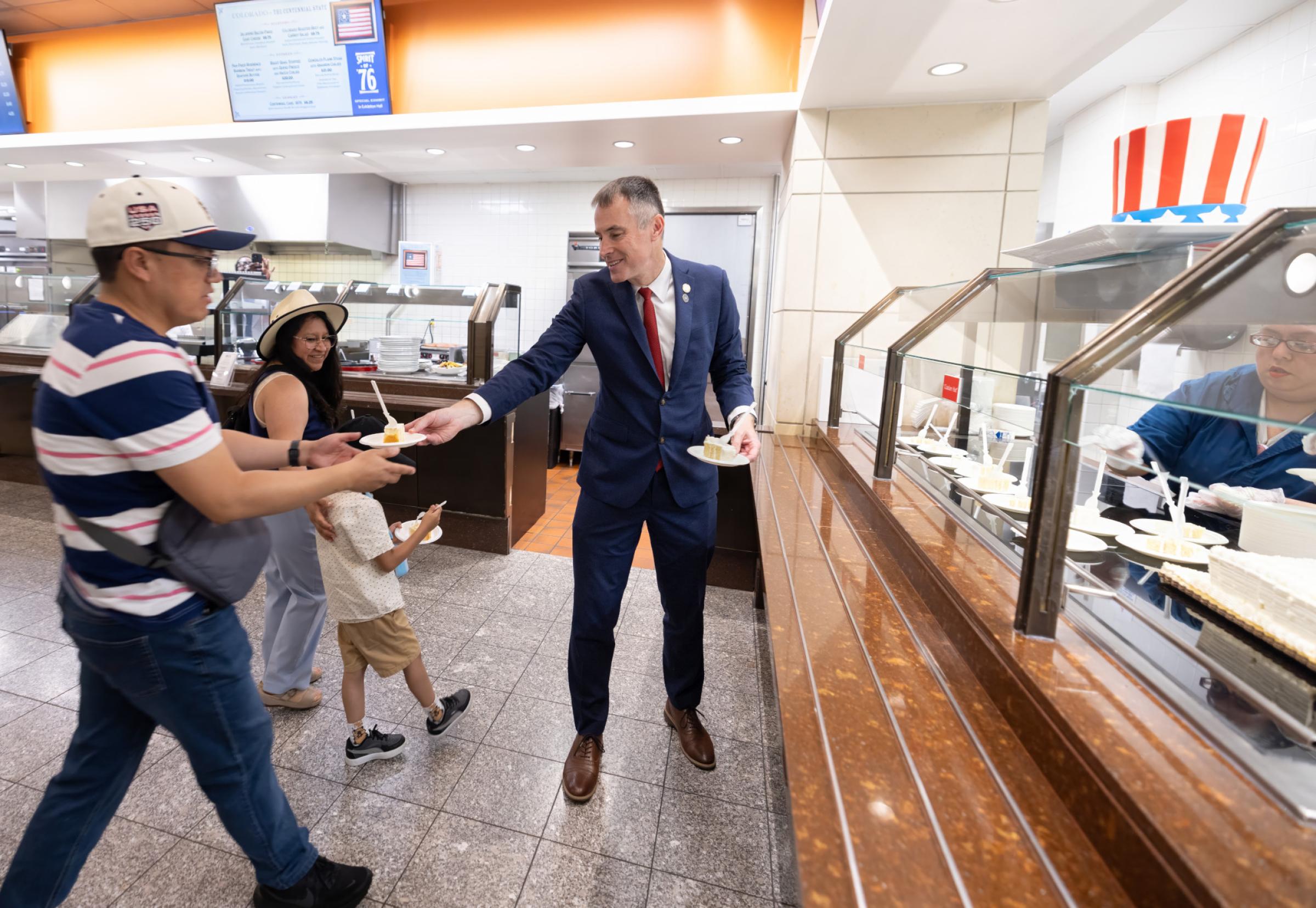 Architect of the Capitol Thomas E. Austin hands out plates with cake to visitors