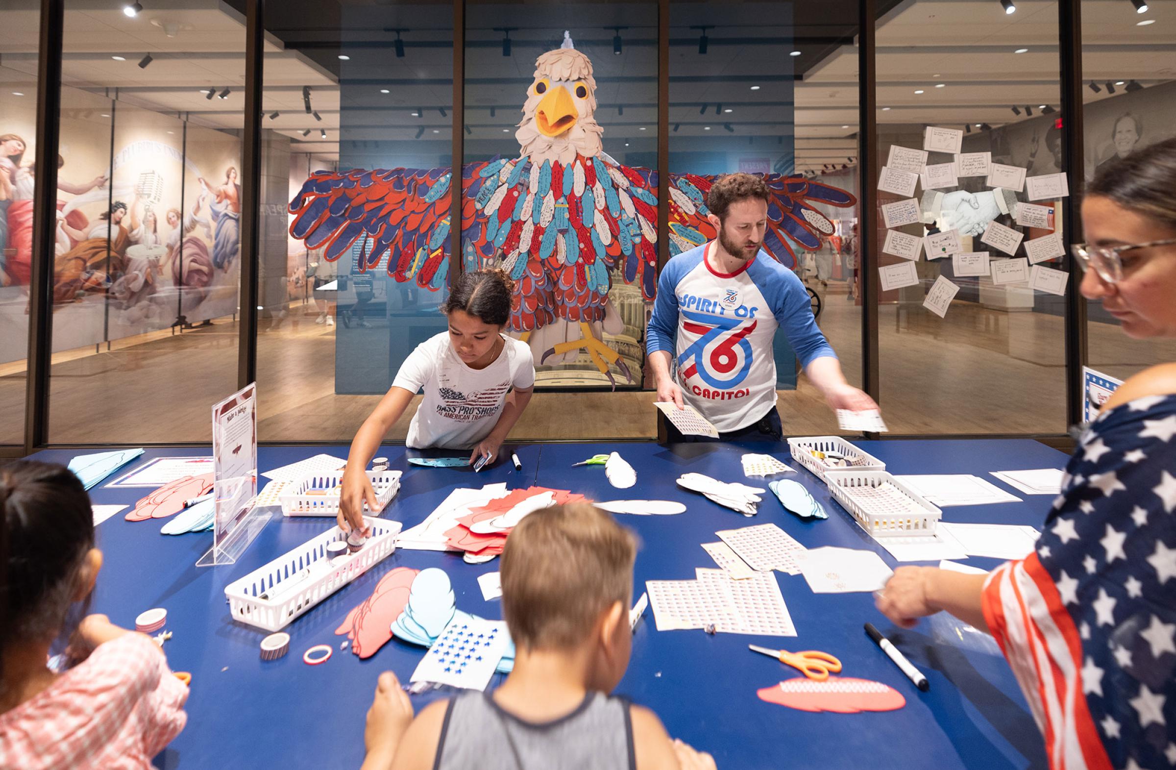 people working on a table in front of Arba the Eagle window cling in Democracy Lab