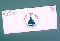 white envelope with an American flag stamp on a green background; the envelope is addressed from Your Name, 123 Apple Street,  City, State 12345 and in place of a recipient address there is a circular stamp with blue and red lettering that says “EXPLORE LEARN CONNECT U.S. CAPITOL WASHINGTON, D.C.” and a blue silhouette of the Capitol Dome  in the center