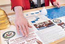 Visitor Guide wearing a red blazer gesturing at cart program materials