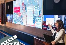 person gestures to a theater screen in Exhibition Hall