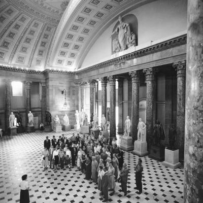 Black and white image of a group standing in a large room with statues