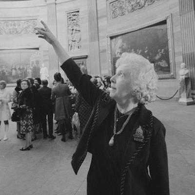Black and white photo of a woman pointing towards the left in a large room