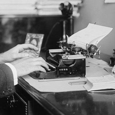 Black and white photograph of hands typing on a typewriter.