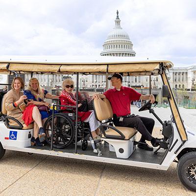 Visitor Guide wearing a red polo and driving a shuttle vehicle