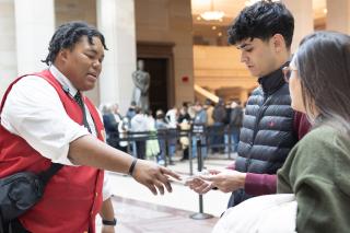 A visitor assistant in a red vest helps guests.