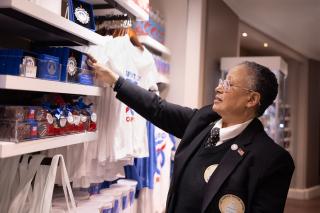 Woman in a black suit with Capitol Visitor Center logo adjusts an ornament for sale in the Gift Shop